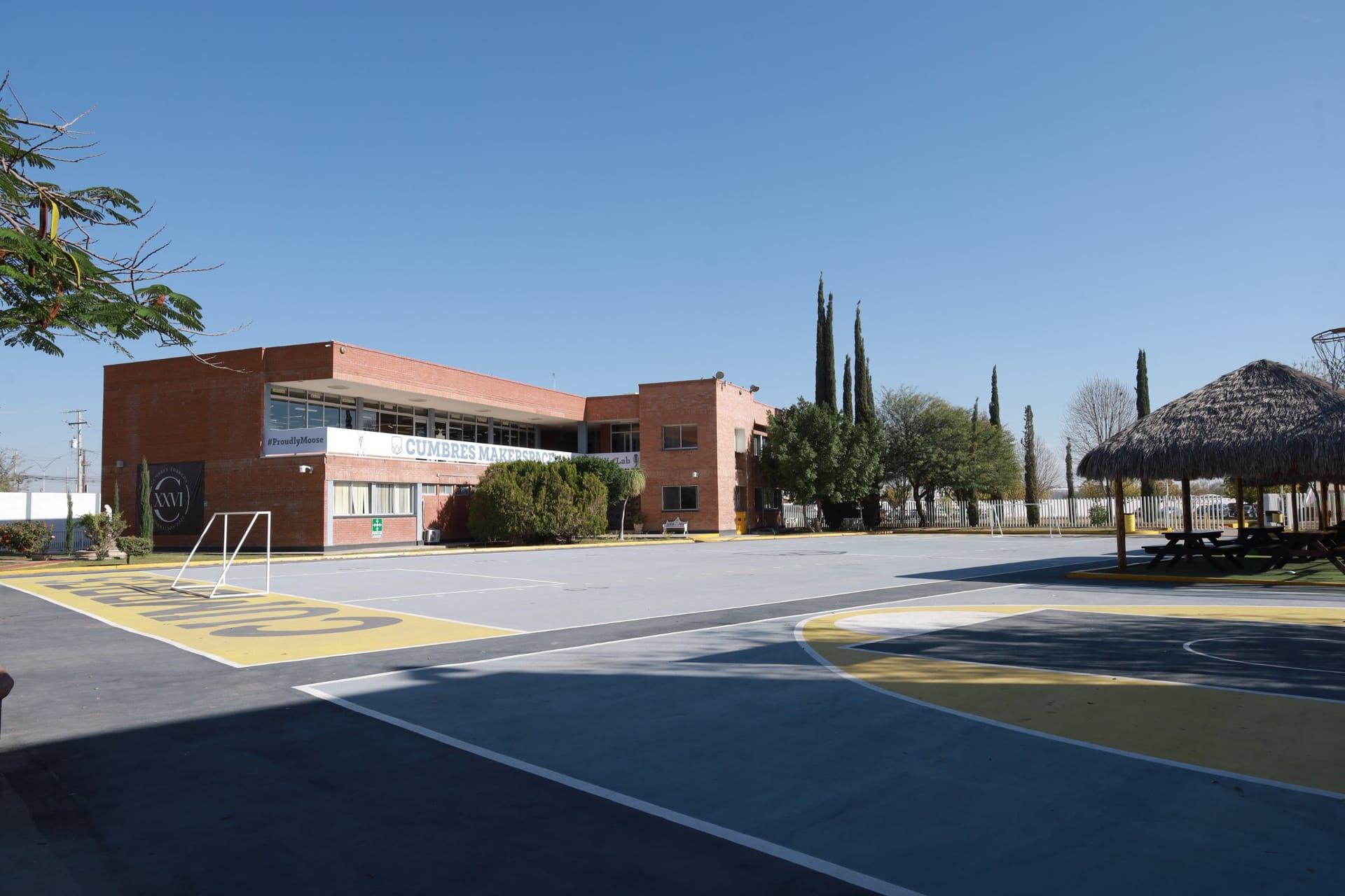 Cancha de básquetbol y área de juego del Instituto Cumbres Torreón con edificio escolar de ladrillo rojo
