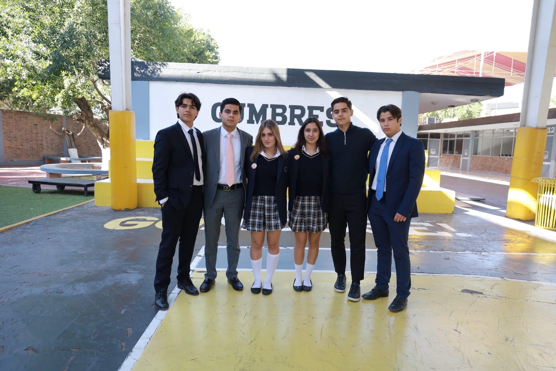 Estudiantes del Instituto Cumbres posando en grupo frente a la entrada "COMBRE" de su colegio